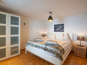 A bedroom with a bed, two bedside lamps, a wall-mounted picture, and a wooden floor. - Berghaus Lichtblick Appartement/Fewo, Bad, WC, 6-Bettwohnung by Interhome (Arosa)