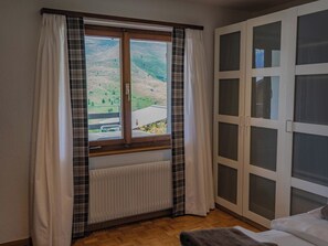 Une pièce dotée d’une grande fenêtre, d’un radiateur et d’une porte-fenêtre coulissante donnant sur un balcon.