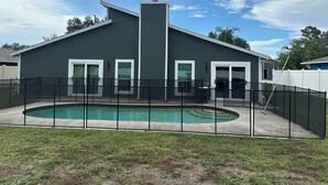 Ett modernt hus med pool, en inhägnad uteplats och en klar himmel.
