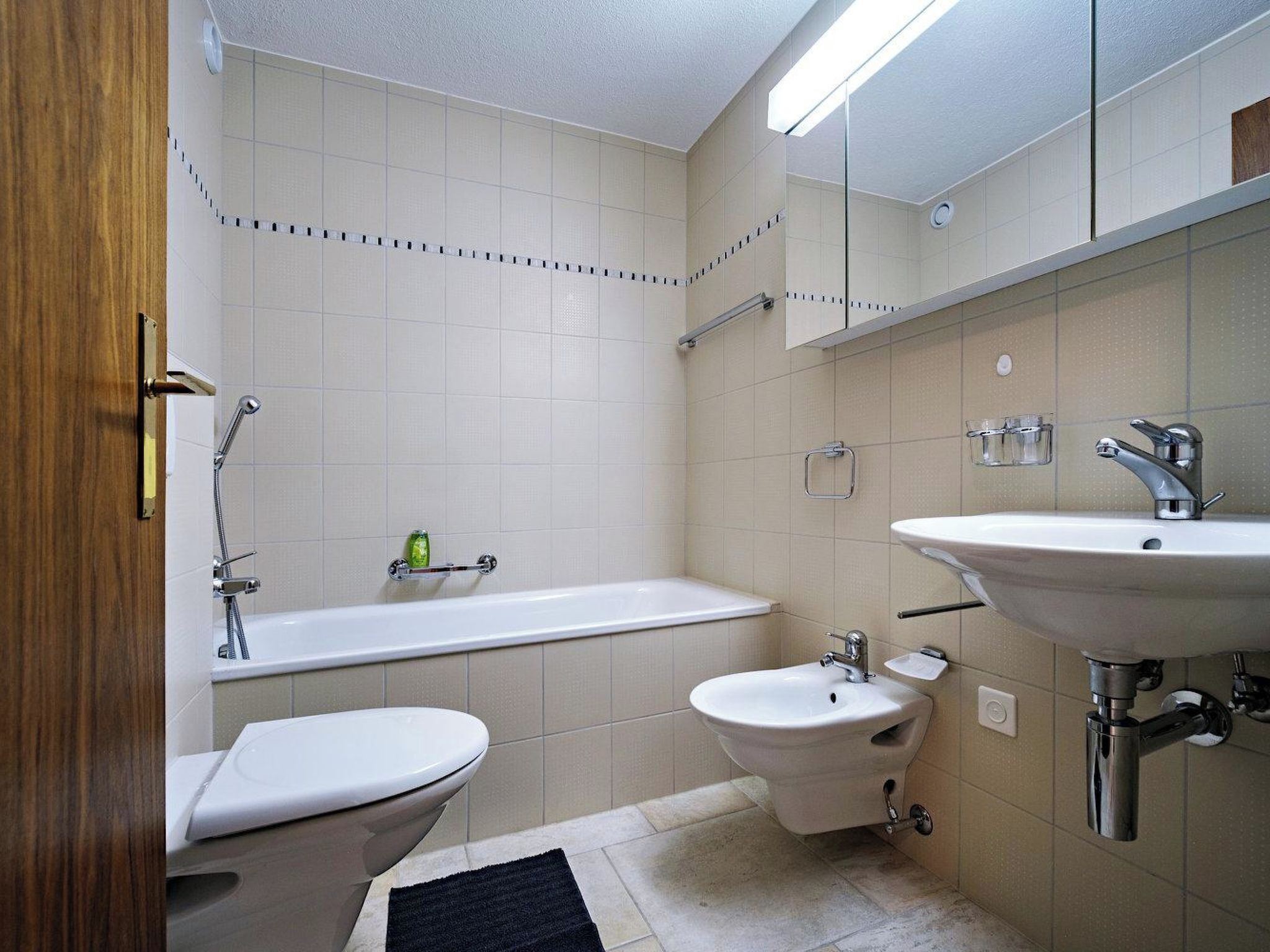 A bathroom with a toilet, bidet, bathtub, and sink.