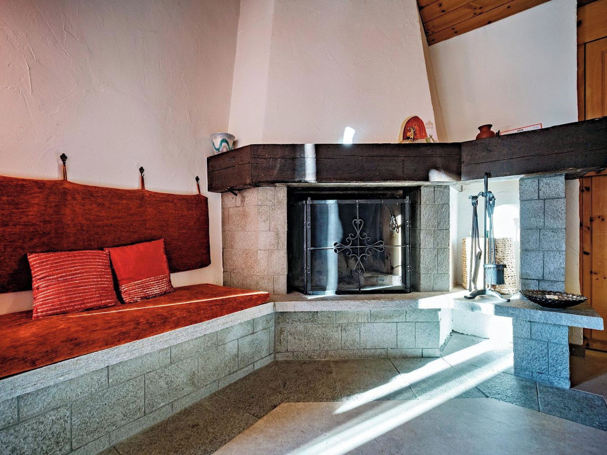 Una habitación acogedora con chimenea, un banco y una pared de piedra.