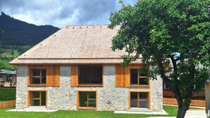 A two-story stone house with a sloped roof, wooden shutters, and a well-maintained lawn. - Benedikt – a cozy apartment steeped in history, perfect for unforgettable getaways (Gröbming)