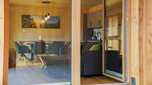 A modern interior with a dining area, a sofa, and a kitchen visible through a glass door. - Benedikt – a cozy apartment steeped in history, perfect for unforgettable getaways (Gröbming)