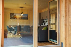 A modern interior with a dining area, a sofa, and a kitchen visible through a glass door. - Benedikt – a cozy apartment steeped in history, perfect for unforgettable getaways (Gröbming)