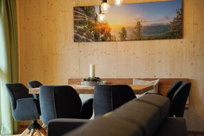 Un coin repas avec une table en bois, des chaises et un tableau représentant un paysage.