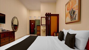 Een hotelkamer met een bed, een dressoir, een televisie, een badkamer met douchegordijn en een schilderij aan de muur.