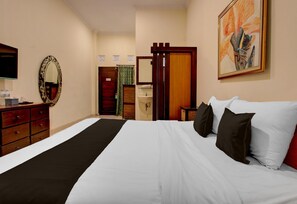 A hotel room with a bed, a dresser, a television, a bathroom with a shower curtain, and a painting on the wall. - Stylish Stay Near Malioboro (Yogyakarta)