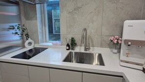 A modern kitchen with a stainless steel sink, a built-in oven, and a water dispenser. - Nana Hostel jonggak (Seoul)