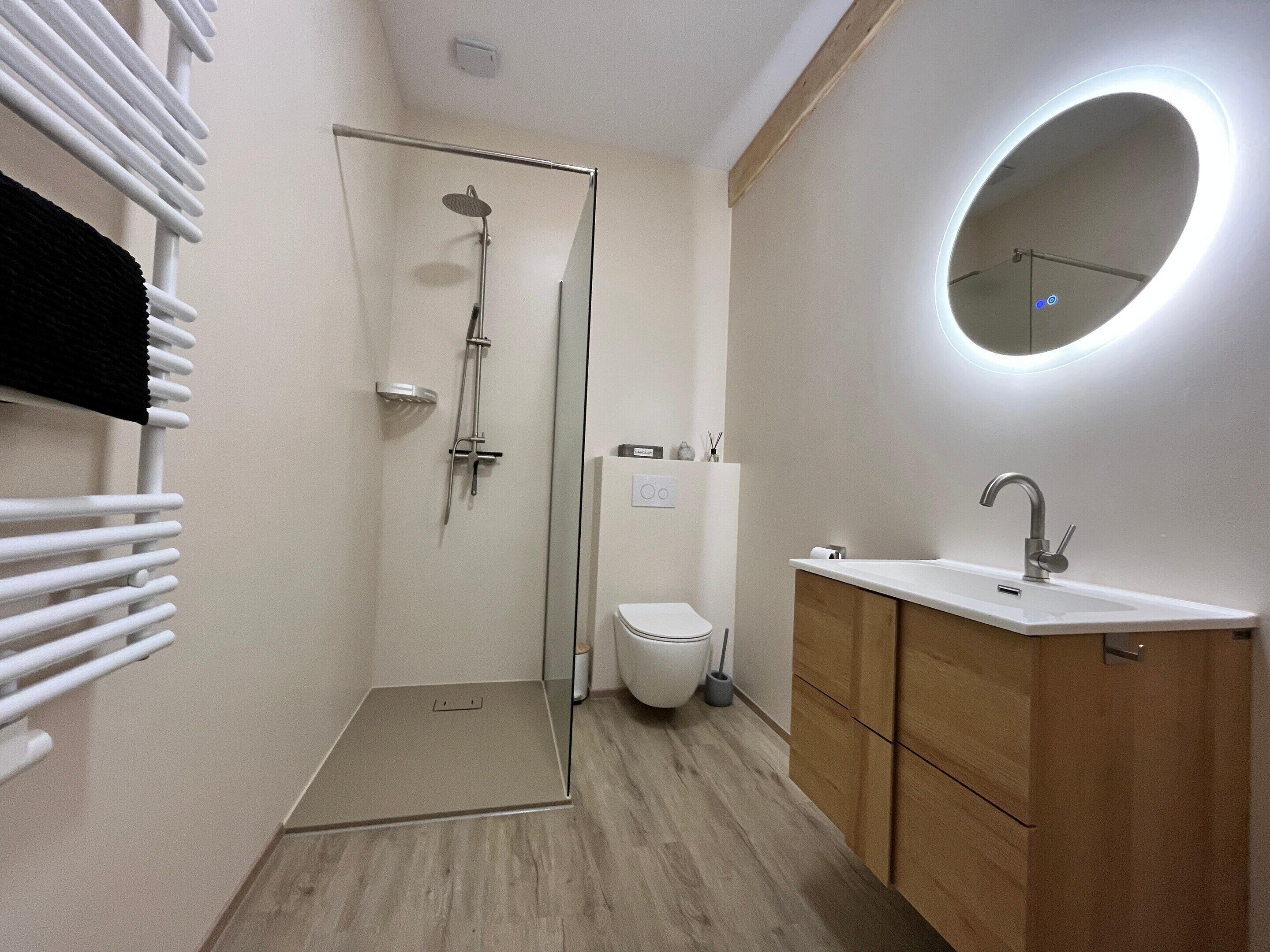 Un baño moderno con ducha, inodoro, lavamanos y espejo.