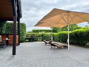 Une terrasse avec une table, des chaises et un grand parasol.