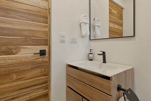 Een badkamer met een houten wand, een witte wasbak, een spiegel en een handdoekhouder.