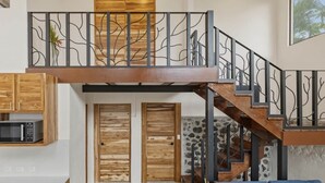 Un espacio habitable de varios niveles con una escalera, puertas de madera y una zona de cocina.