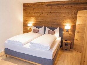 A double bed with white linens, two bedside lamps, and a small wooden nightstand. - Terra Alpina Appartement/Fewo, Bad, WC, 10-Bettwohnung by Interhome (Arosa)