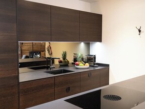 A modern kitchen with dark wood cabinets, a stainless steel sink, and a fruit bowl on the counter. - Terra Alpina Appartement/Fewo, Bad, WC, 10-Bettwohnung by Interhome (Arosa)