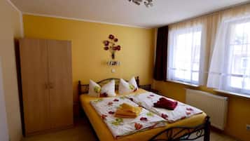 Un dormitorio con cama, armario, radiador y ventana con cortinas.
