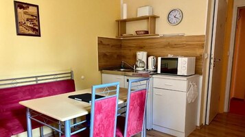 Una kitchenette compacta con microondas, cafetera y un reloj en la pared.
