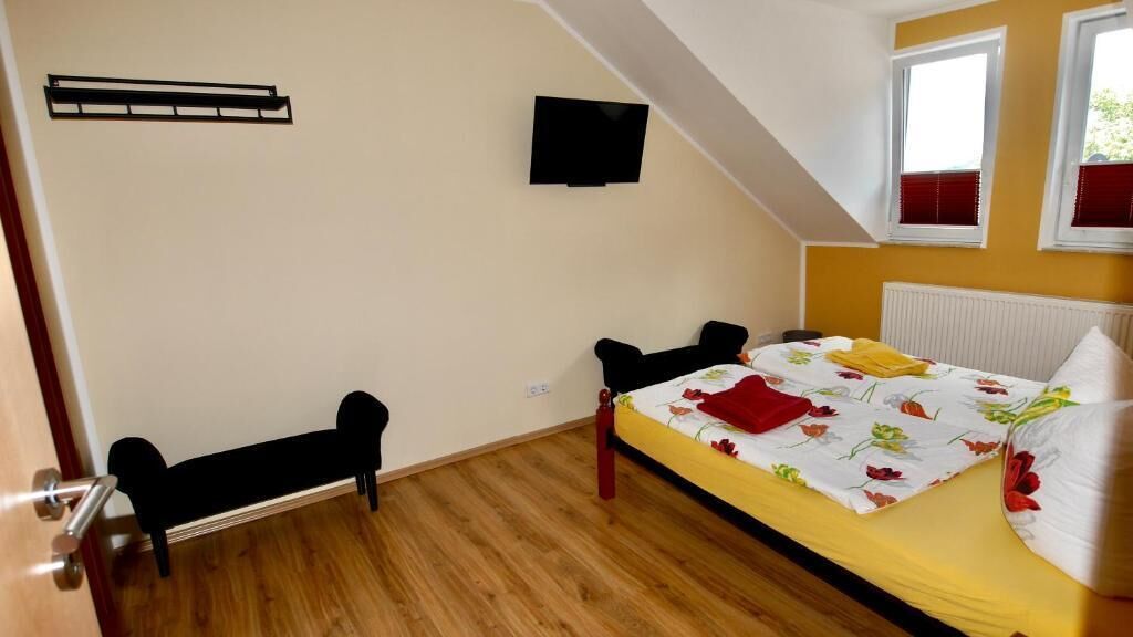 Ein Schlafzimmer mit Bett, Schreibtisch, Stuhl, Fernseher und Fenster.