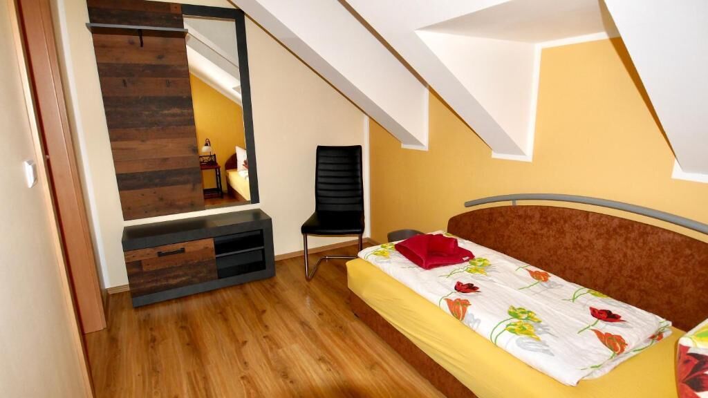 Ein Schlafzimmer mit einem Bett, einem Sessel, einem Spiegel und einer Holzwand.