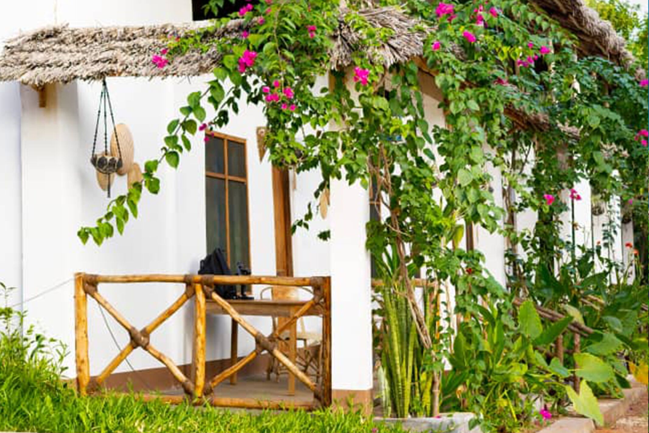 Une maison rustique avec un toit de chaume, une table en bois et un panier suspendu.