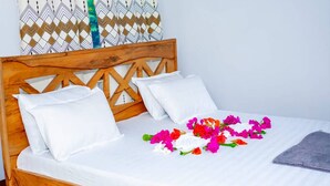 A bed with white bedding, a wooden headboard, and a floral arrangement on the bed.