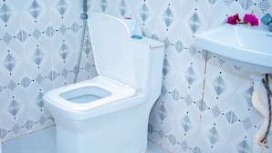 A bathroom with a white toilet, a white sink, and a patterned wall.