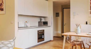 A compact kitchen with white cabinets, a microwave, and a built-in oven. - Charming Studio 4P - Milano Centrale (Milan)
