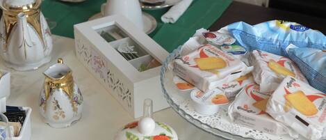 A table with a teapot, a pitcher, a box, and a plate with pastries.