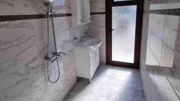 Un bagno con doccia, lavandino e mobile.