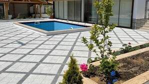 Uma área residencial com piscina, jardim com plantas e um edifício com telhado vermelho.