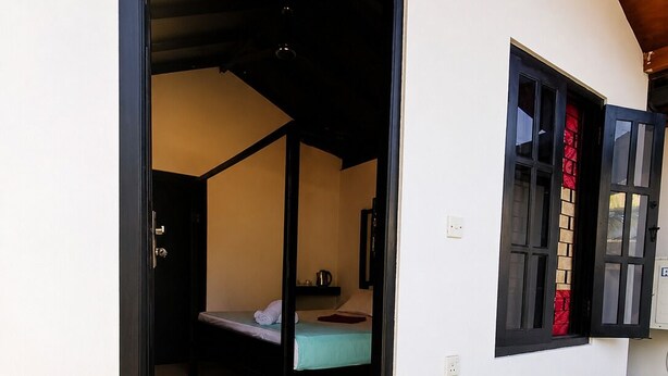 Een kamer met een bed, een kleintje tafeltje en een raam met uitzicht.