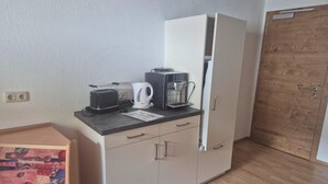 Pieni keittiönurkkaus, jossa on leivänpaahdin, kahvinkeitin ja kaappi.
