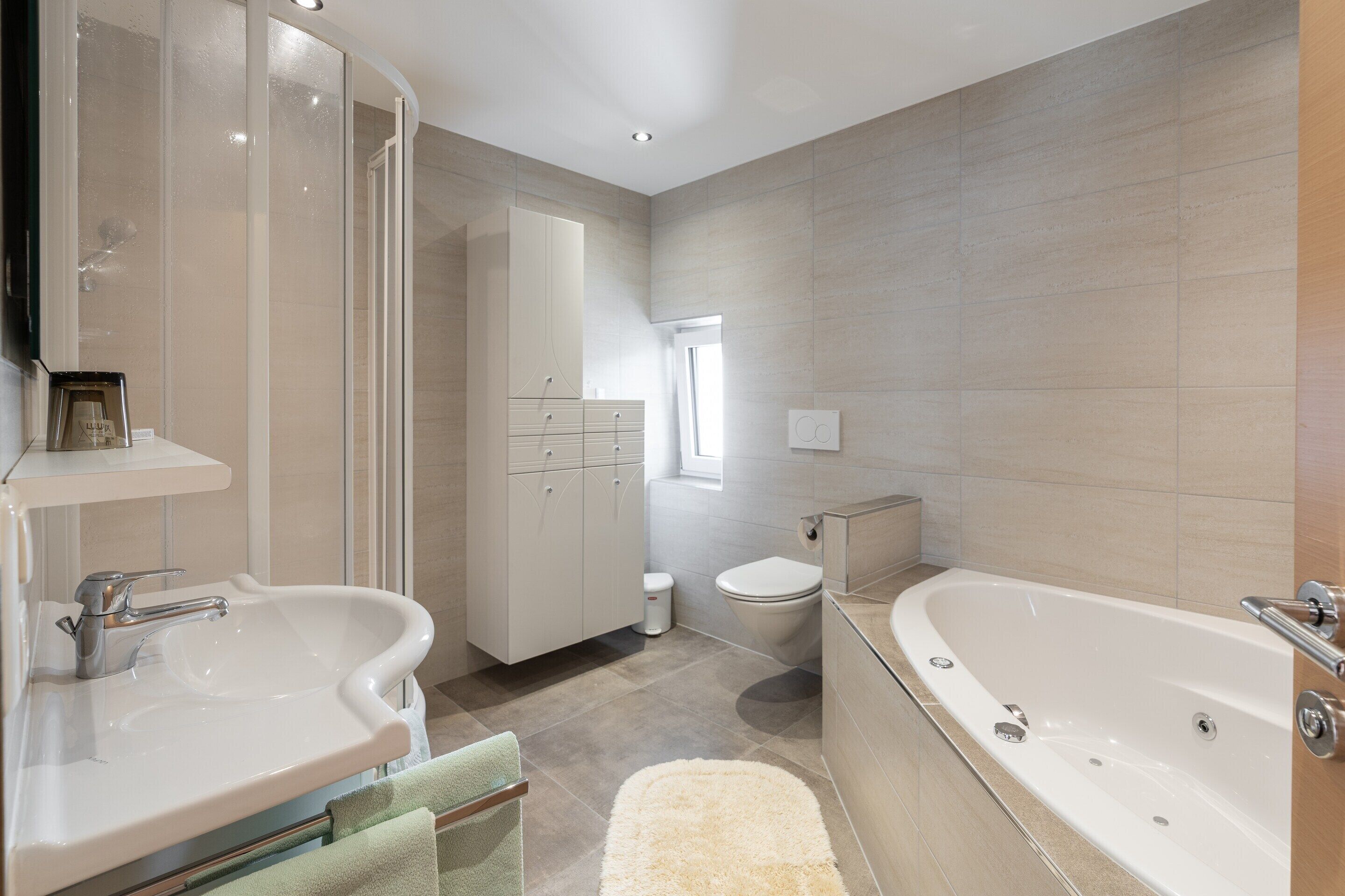 A modern bathroom with two sinks, a toilet, and a bathtub.