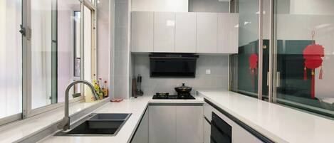 A modern kitchen with white cabinets, a black stove, and a glass backsplash.