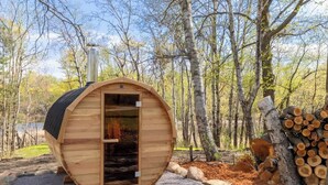 Eine Holzhütte mit Tür, umgeben von Bäumen und Baumstämmen.