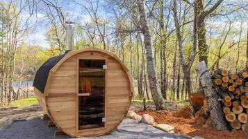 A wooden cabin with a door, surrounded by trees and logs.