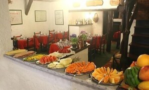 Un bufé con diferentes opciones de comida, mesas con manteles rojos y una zona de bar.