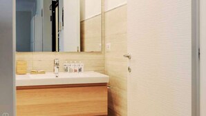 Ein Badezimmer mit einem weißen Waschbecken, einem Holfach und einem Spiegel darüber.