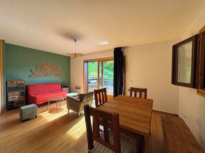 Ein Essbereich mit einem Holztisch und Stühlen, einem roten Sofa und einer Wanddekoration.