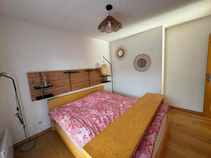 Ein Schlafzimmer mit einem Bett, einem Holz-Kopfteil, einem Nachttisch, einer Stehlampe und dekorativen Wandspiegeln.