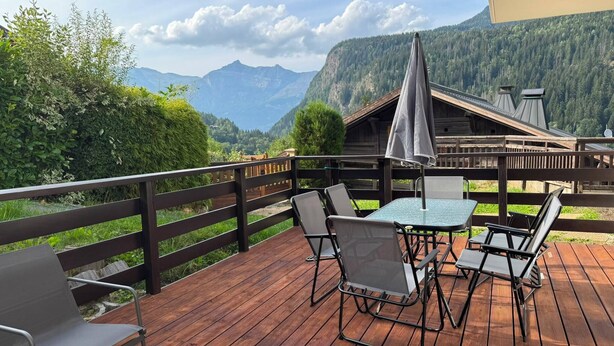 Eine Holzterrasse mit Sitzgelegenheiten und Blick auf die Berge.