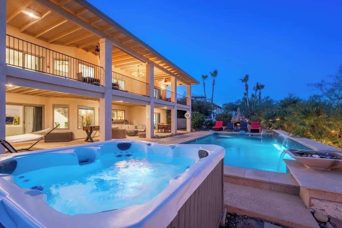 A two-story building with a pool, hot tubs, and outdoor seating.