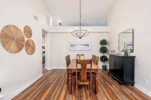 A dining area with a wooden table and chairs, a chandelier, a black console table, and a mirror on the wall. - MountainView Estate+HeatedPool+Spa+Firepits (Fountain Hills)