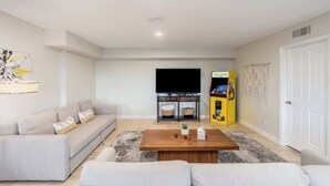 Een woonkamer met een bank, een salontafel, een televisie en een gameconsole.