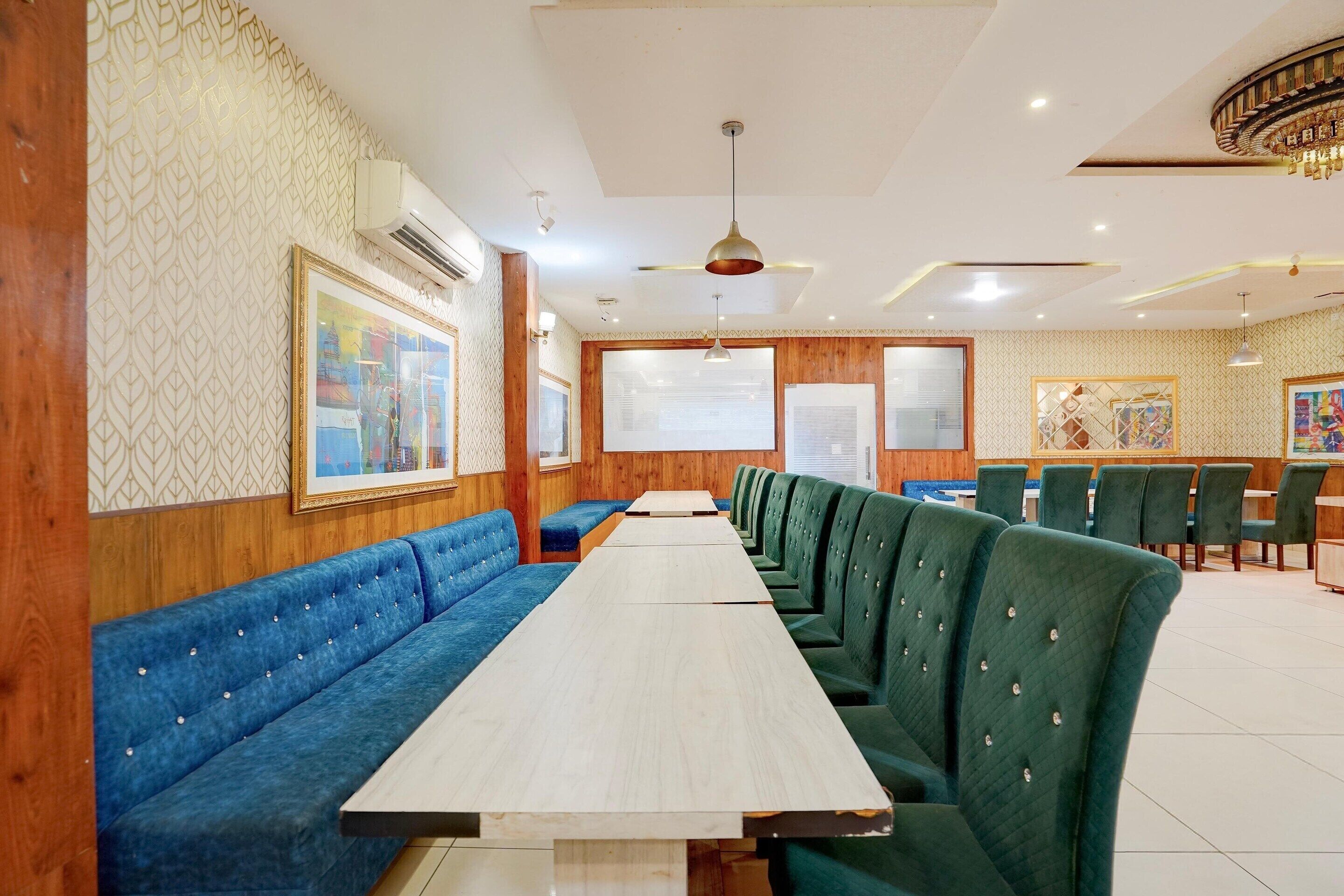 A restaurant with long wooden tables and green upholstered booths.