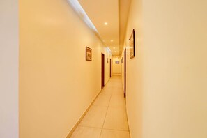 A hotel hallway with doors on both sides, recessed lighting, and framed pictures on the walls.