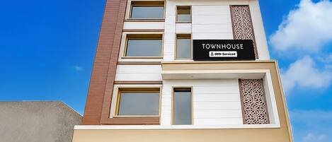 Een meerhoog gebouw met een bord waarop 'TOWNHOUSE' en 'oyo-Serviced' staat.