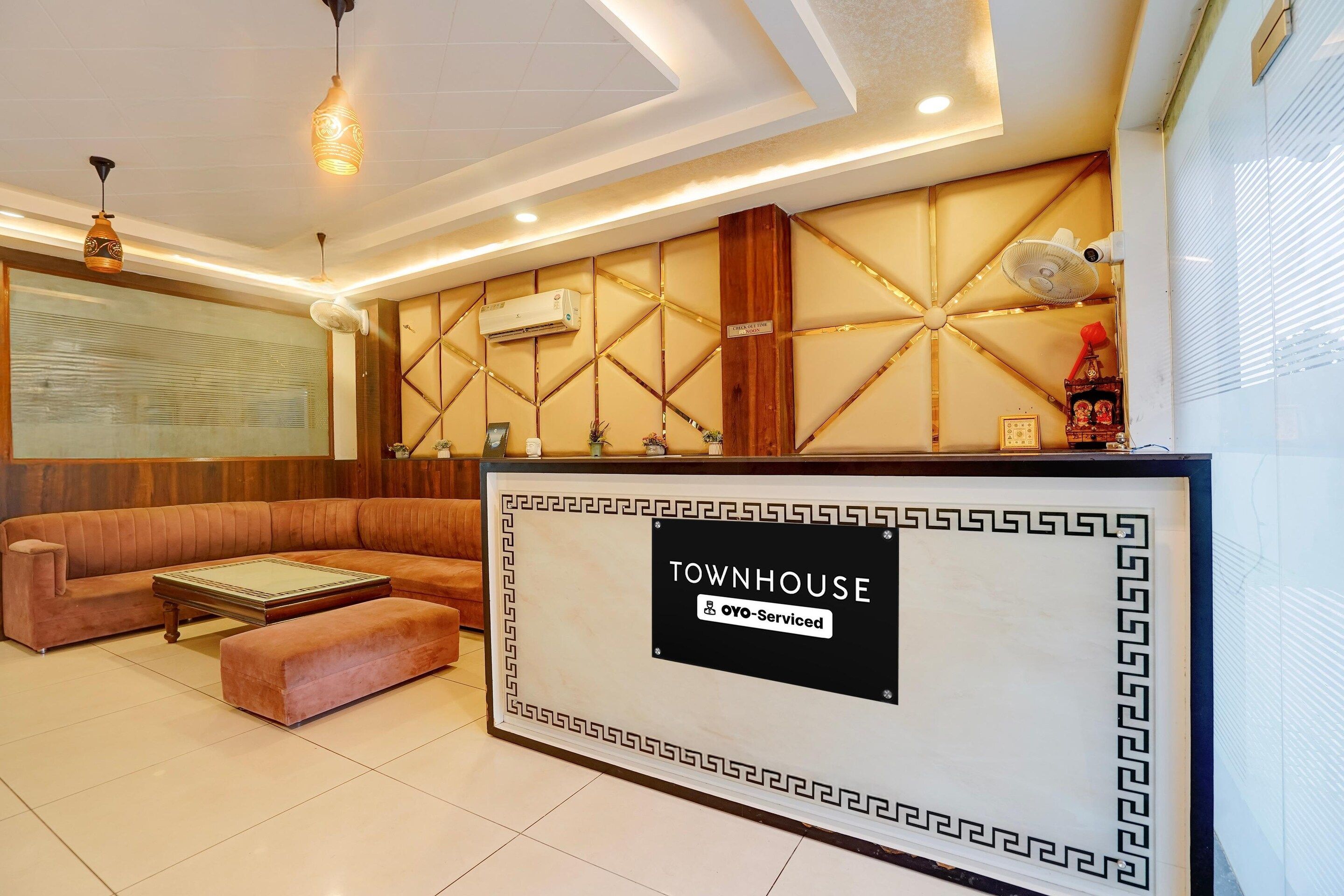 Un espace d’accueil comprenant un canapé, une table basse et un panneau indiquant « TOWNHOUSE OYO – Services hôteliers ».