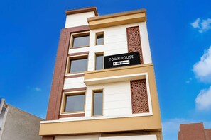 Un immeuble à plusieurs étages portant une enseigne indiquant « TOWNHOUSE » et « OYO-Serviced ».