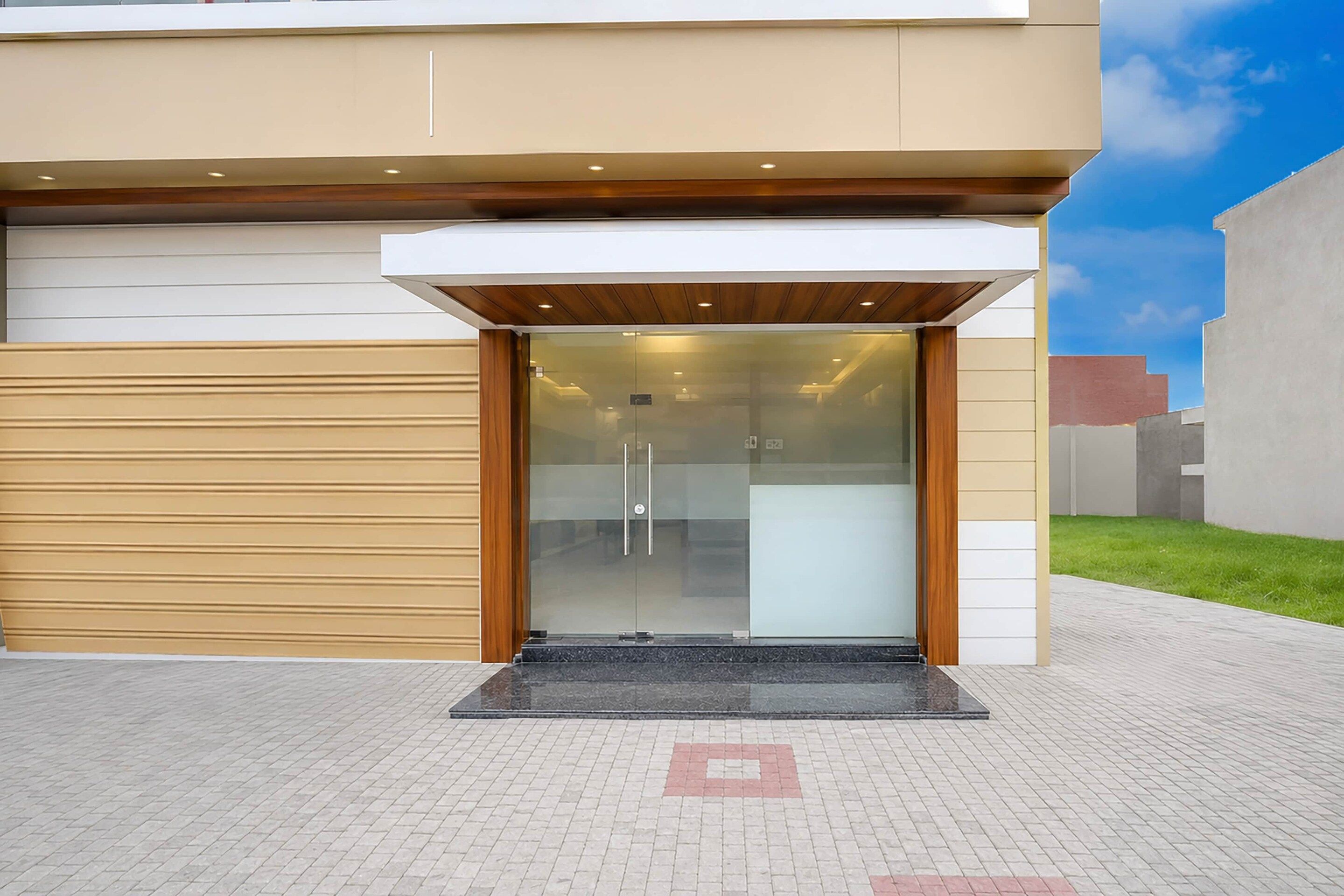 Ein moderner Gebäudeeingang mit Glastür und einem Holzüberstand.