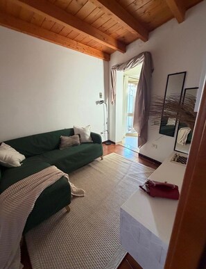 Ein Wohnzimmer mit einem grünen Sofa, einem weißen Tisch und einer Holzbalkendecke.